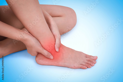 Close up suffering male pain in ankle on blue background.