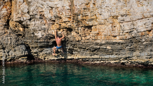 Young athletic man climbing sea cliffs without rope or harness in Croatia © andreaobzerova