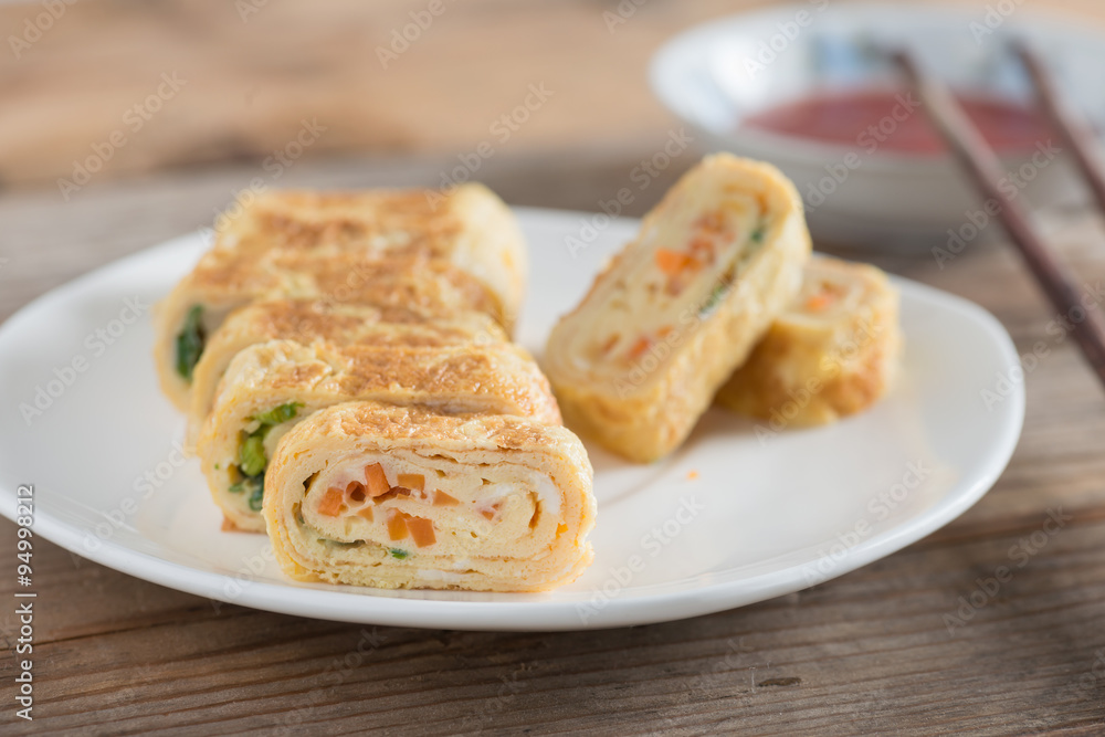 Eggs roll with carrot and onion on white plate. Selective focus. Eggs roll with carrot and onion on white plate. Selective focus.