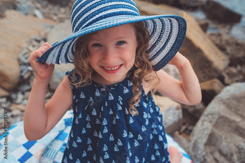 happy child girl at sea in stripe hat on summer vacation