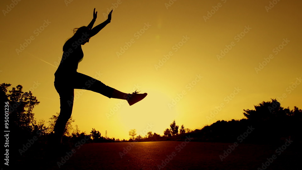 SLOW MOTION: young woman doing gymnastic wheel at sunset SLOW MOTION: young woman doing gymnastic wheel at sunset