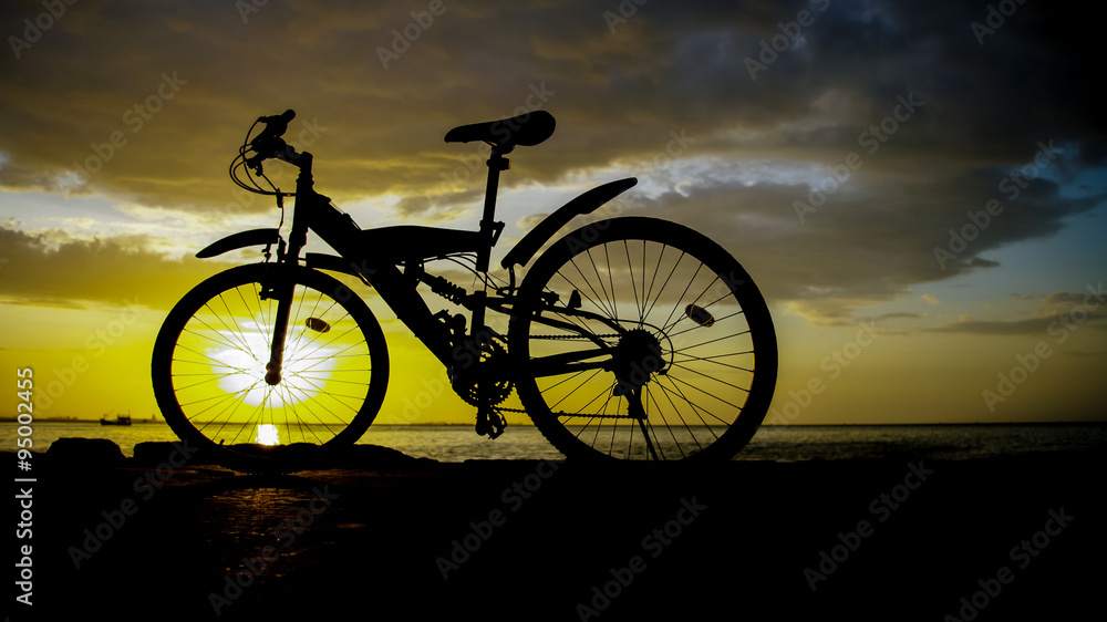Silhouette of mountain bike with sunset sky at sea Silhouette of mountain bike with sunset sky at sea