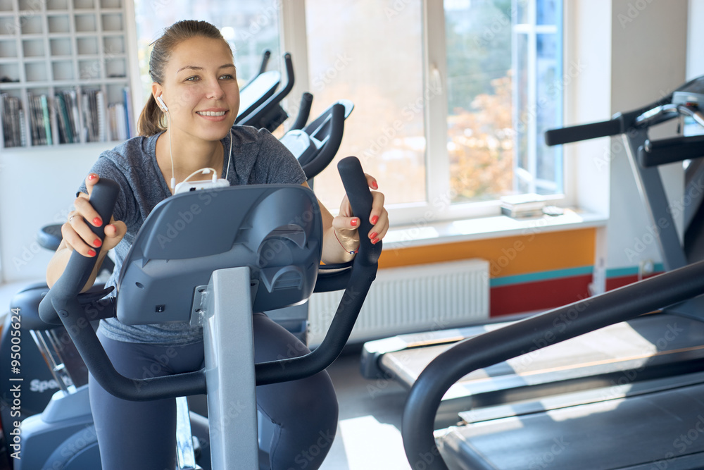 happy woman is engaged on a stationary bike happy woman is engaged on a stationary bike