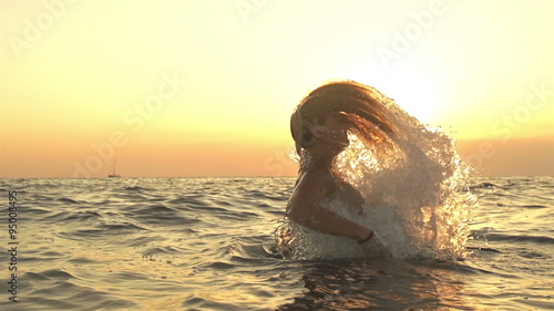 SLOW MOTION: Young woman splashes water with her hair photo