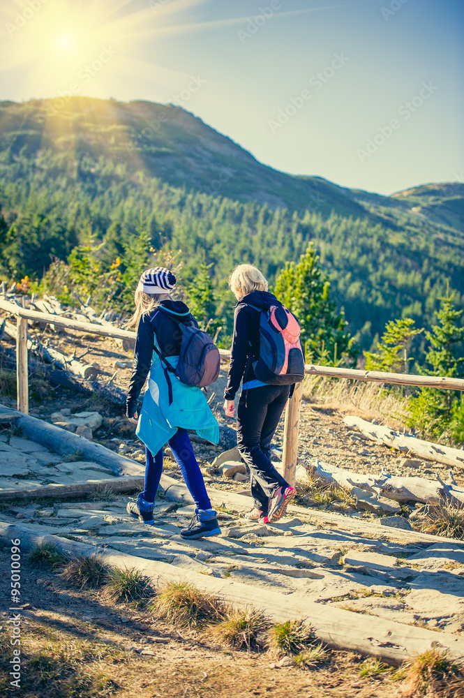 Obraz premium Mother with daughter hikers trekking in mountains.