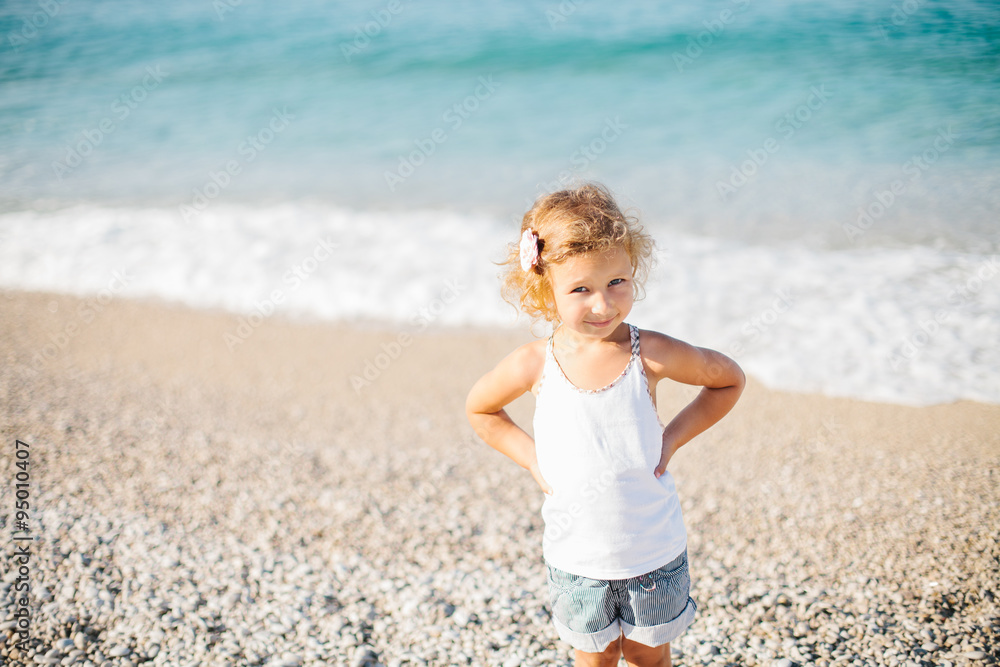 Adorable happy smiling little girl with curly hair on beach vaca Adorable happy smiling little girl with curly hair on beach vaca