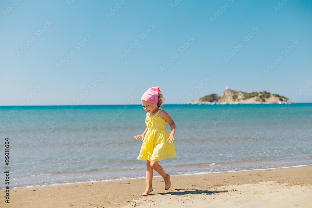 Adorable happy smiling little girl with curly hair on beach vaca