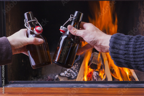 happy couple cheering with beer bottles at skiing hut