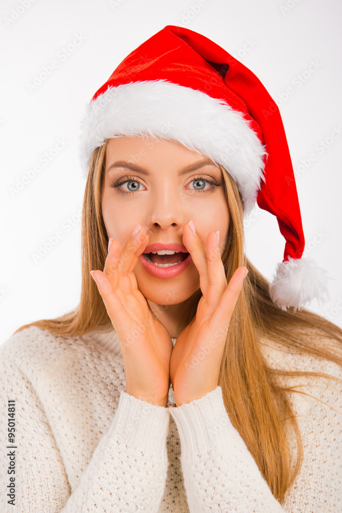 Cute young woman with santa's hat tells the news holds hand nea Cute young woman with santa's hat tells the news holds hand nea