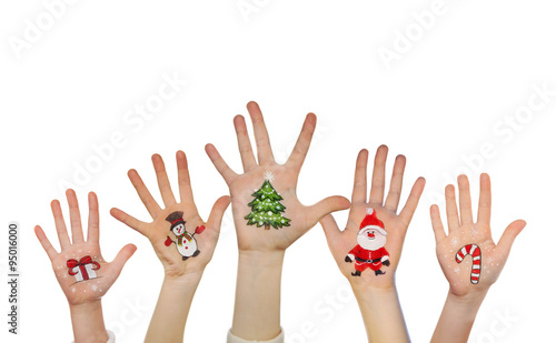 Children's hands raising up with painted Christmas symbols: Santa Claus, Christmas tree, Snow man, present box