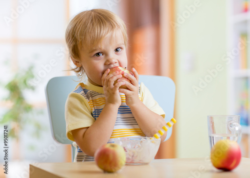 child eating apple at dinne...