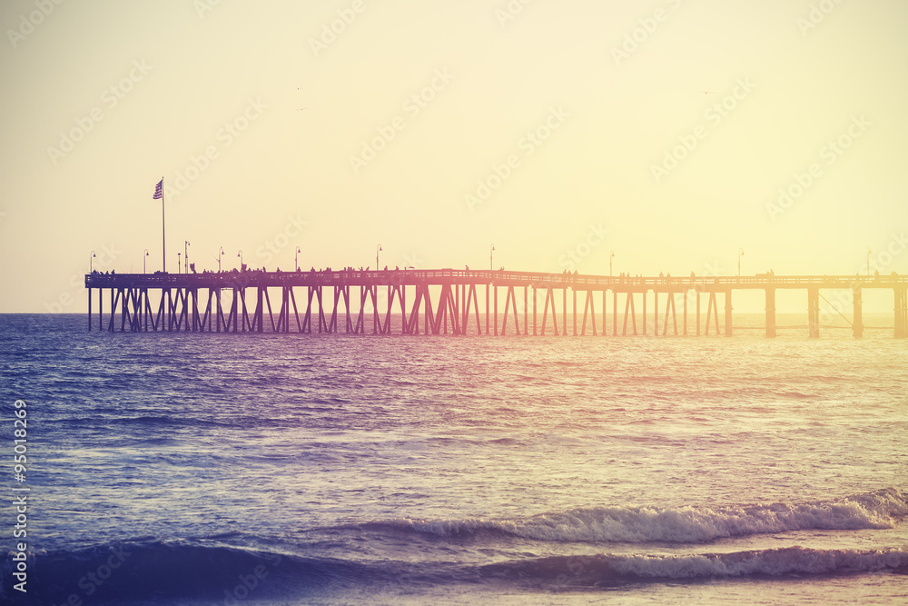 Vintage toned wooden pier on beach at sunset, California, USA