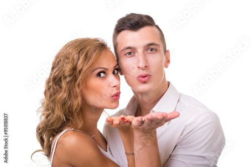 Happy young couple sending a blow kiss to the camera against isolated white
