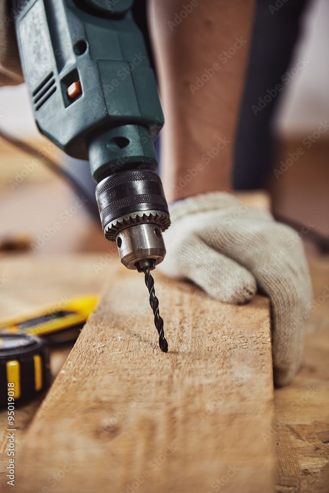 Close-up portrait of male artisan drilling lumber in his shop. Concept of technology and equipment. Close-up portrait of male artisan drilling lumber in his shop. Concept of technology and equipment.