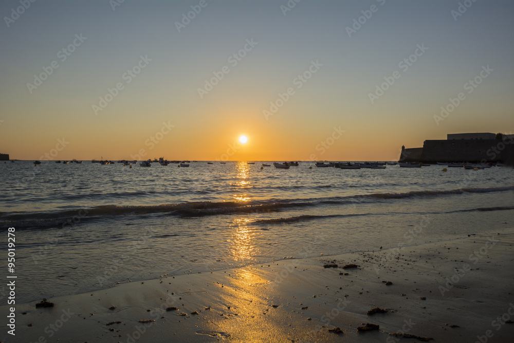 Beautiful sunset on a beach with fishing boats at the bottom, Ca