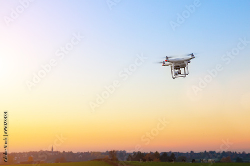 Unbemannte RC Drohne fliegt auf einem freien Feld bei Sonnenuntergang photo
