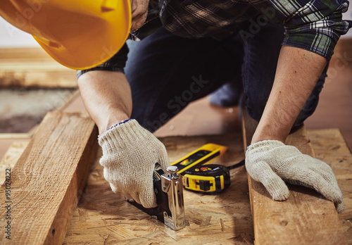 Photos Young man builder in workwear repairing wooden furniture in a house