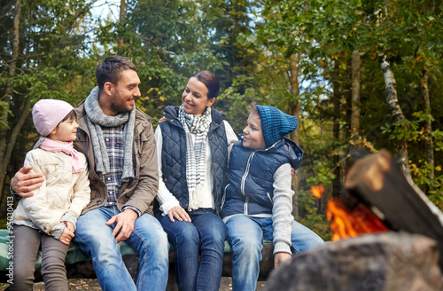happy family sitting on bench at camp fire © Syda Productions