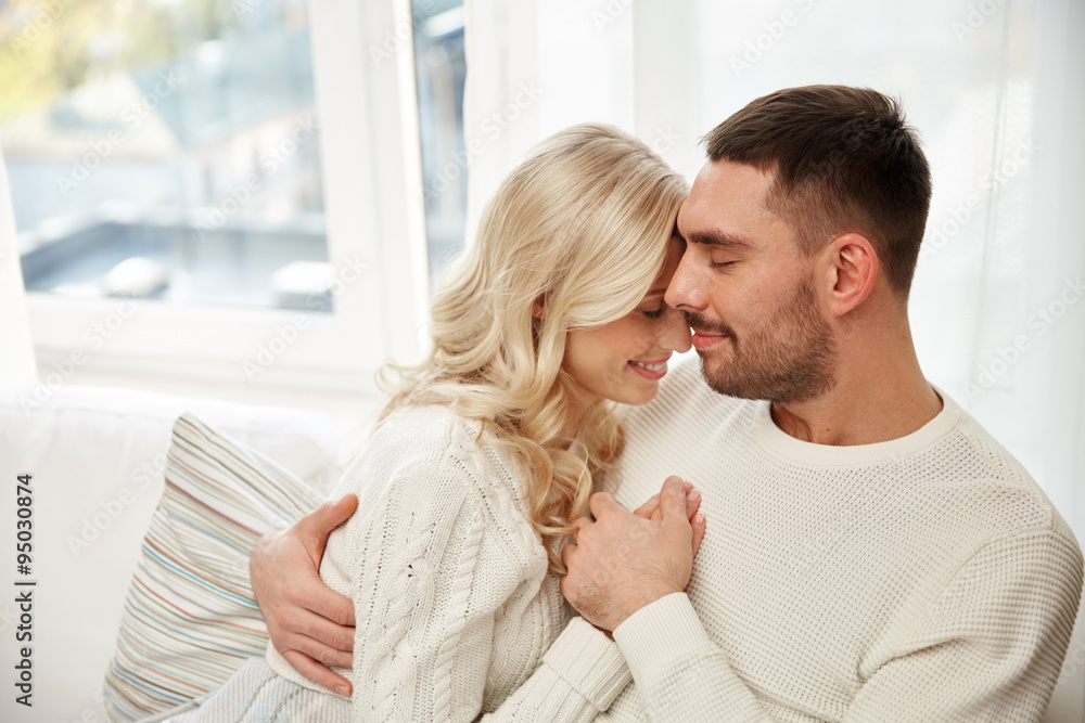 happy couple covered with plaid on sofa at home happy couple covered with plaid on sofa at home