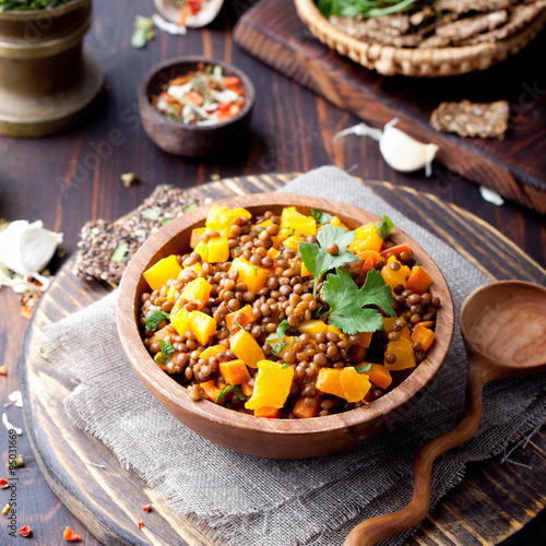 Lentil with carrot and pumpkin ragout in a wooden bowl.