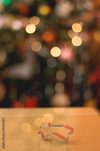 Christmas cookie cutter shaped like falling star. Beautiful colorful bokeh in the background. 