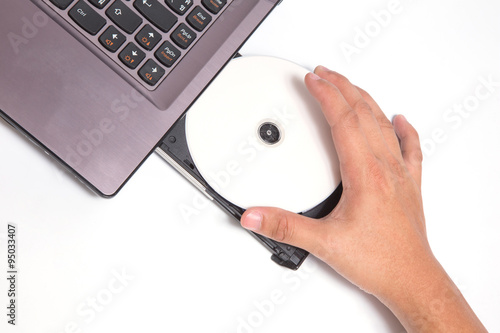 Hand holding New CD/DVD inside optical disk drive bay