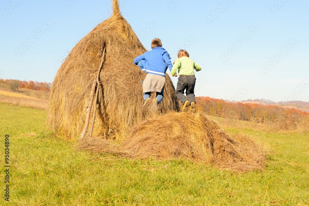 Brother and sister jumping on a haystack Brother and sister jumping on a haystack