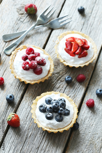Dessert tartlets with berries on grey wooden background