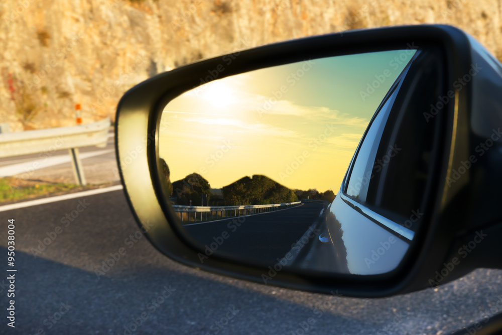 street lit by the sunset reflected in the rearview mirror of a car