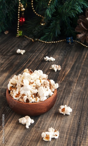 popcorn in a wooden plate on the background of Christmas trees