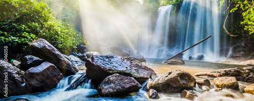 Tropical waterfall in jungle with sun rays