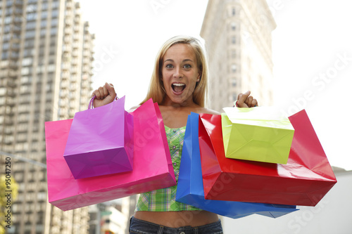 A woman holding up her shopping bags with a happy and satisfied look of accomplishment on her face