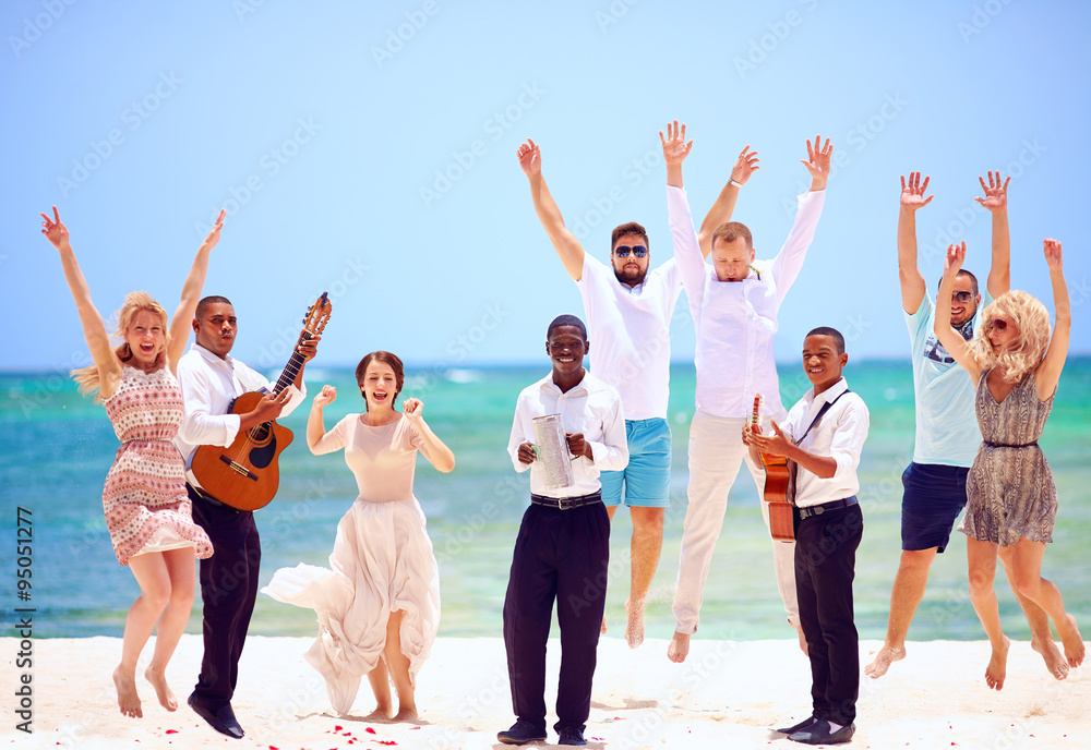 group of happy people on celebration the exotic wedding with musicians, on tropical beach