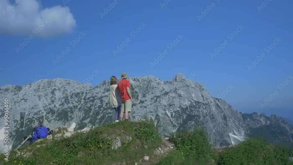 AERIAL: Young couple admiring the view on mountain peak AERIAL: Young couple admiring the view on mountain peak