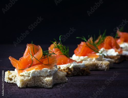 Row of festive canapes in star shape with smoked salmon on dark