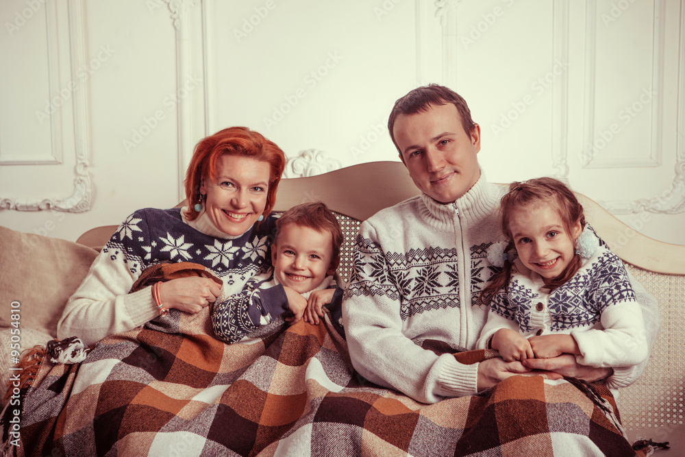 Beautiful family in the sweaters is sitting on the sofa
