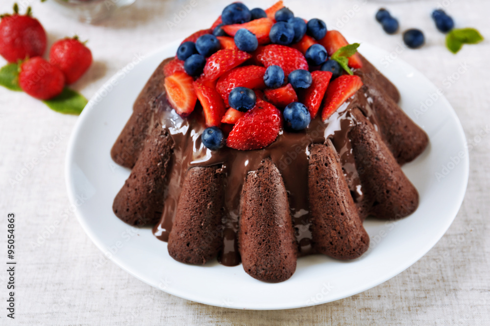 Tasty chocolate muffin with glaze and berries on table close up Tasty chocolate muffin with glaze and berries on table close up