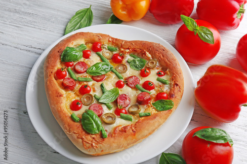 Delicious heart shaped pizza with vegetables on wooden background, close up