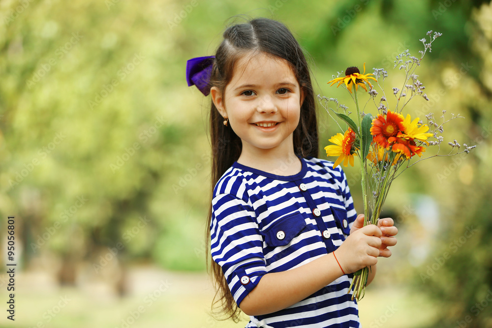 Portrait of happy little girl with flowers in park
