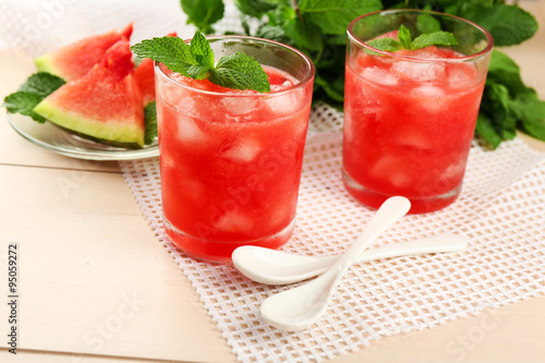Cold watermelon drinks in glasses, on wooden table background