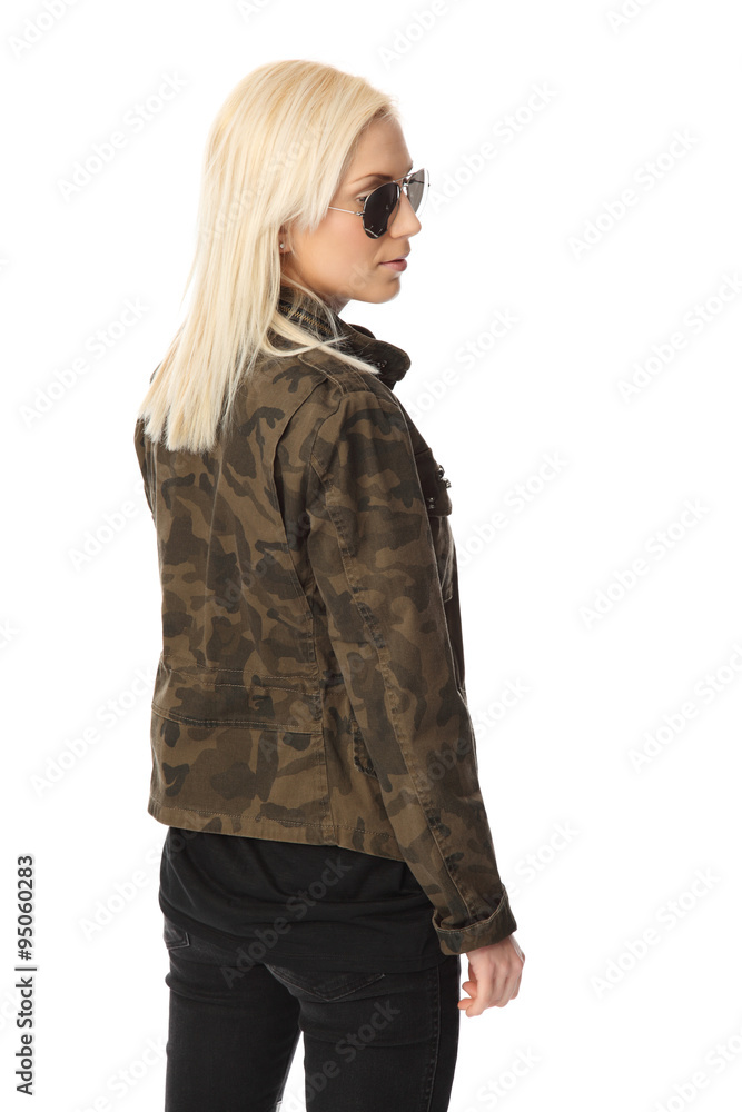 An attractive woman standing against a white background wearing a military jacket with big sunglasses. Macho looking. An attractive woman standing against a white background wearing a military jacket with big sunglasses. Macho looking.