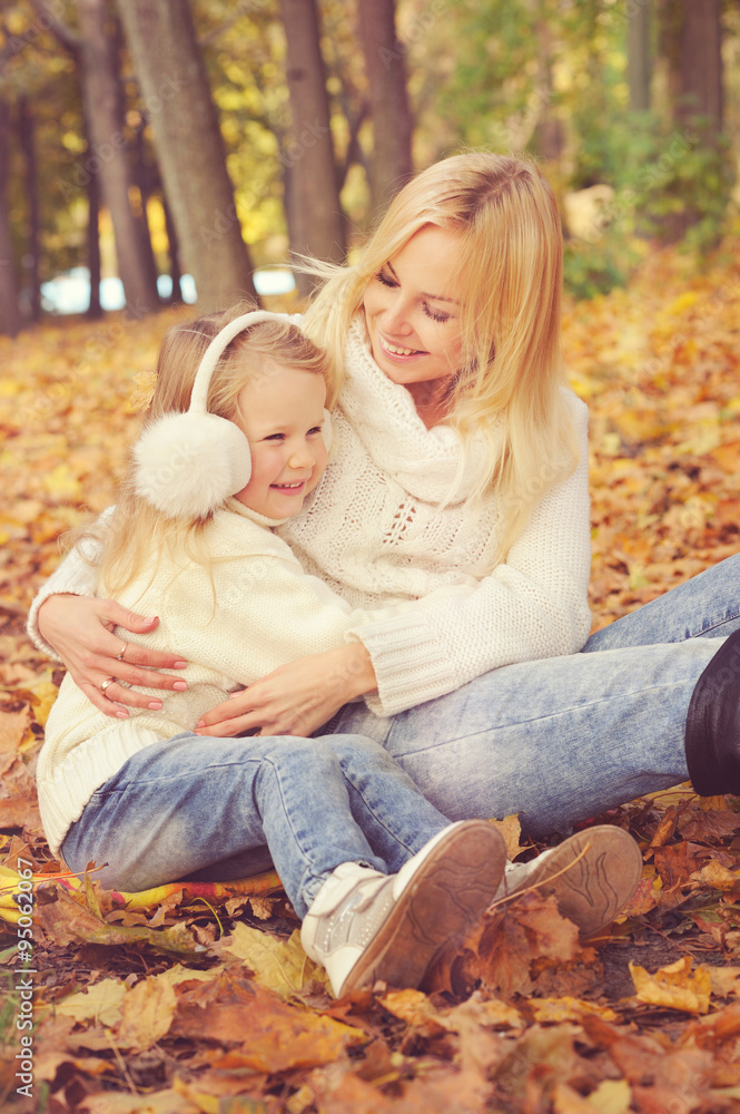 Happy family mother and little daughter play cuddling in autumn park. Happy family mother and little daughter play cuddling in autumn park.