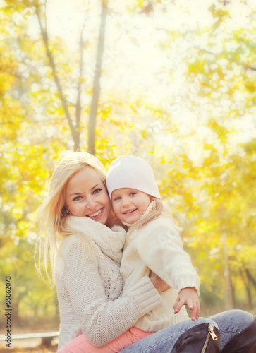 Portrait of a happy family with beautiful blonde mother and little daughter resting in park.