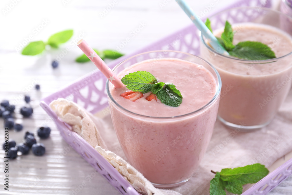 Tasty strawberry, blueberry and milk yogurt on server in a row against light wooden background Tasty strawberry, blueberry and milk yogurt on server in a row against light wooden background