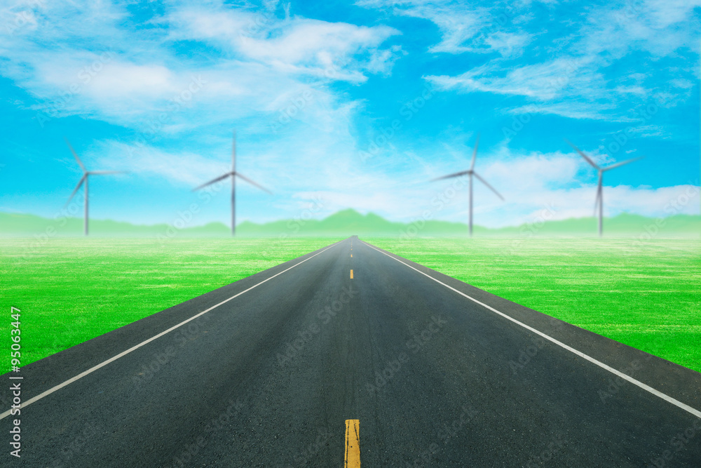asphalt road through the green field with wind turbine and blue