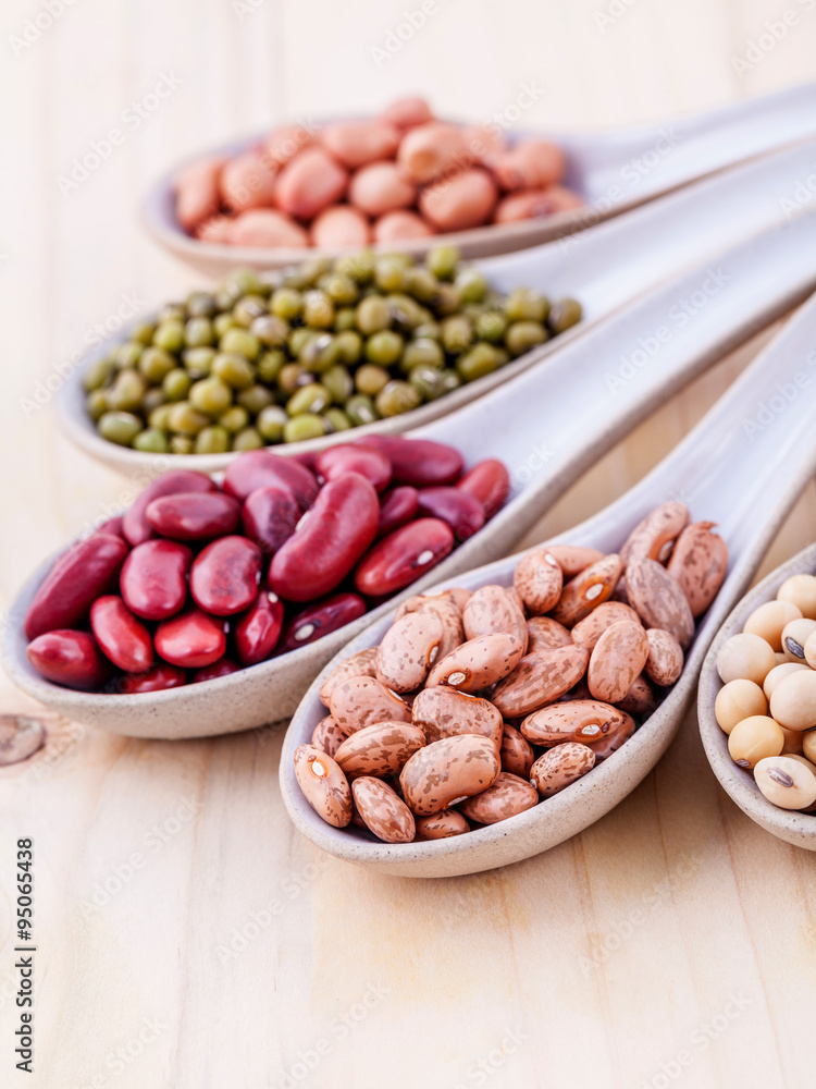 Assortment of beans and lentils in wooden spoon on wooden backgr Assortment of beans and lentils in wooden spoon on wooden backgr