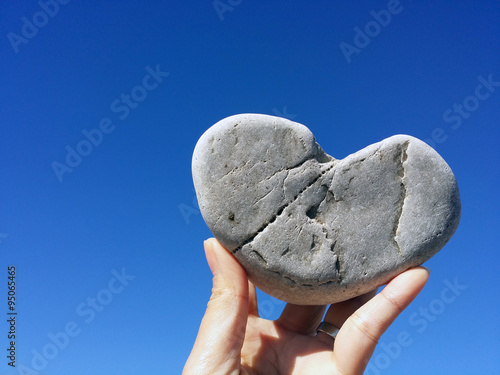 holding heart rock on the blue sky