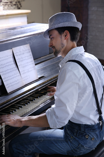 Photography Handsome young man in hat making piano music