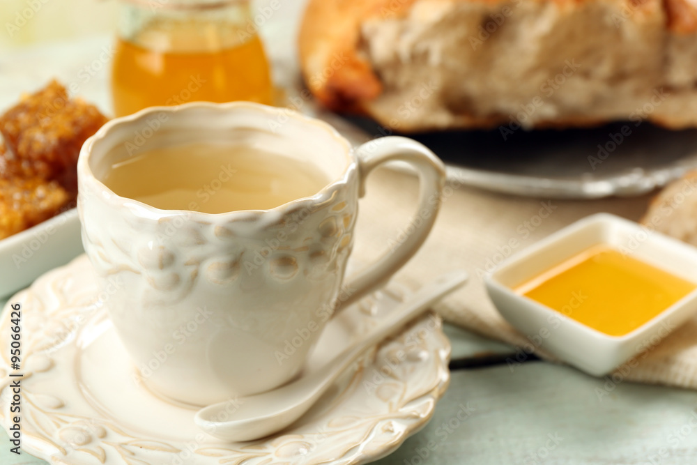 Honeycomb, bowl with honey, cup with herbal tea on color wooden background Honeycomb, bowl with honey, cup with herbal tea on color wooden background