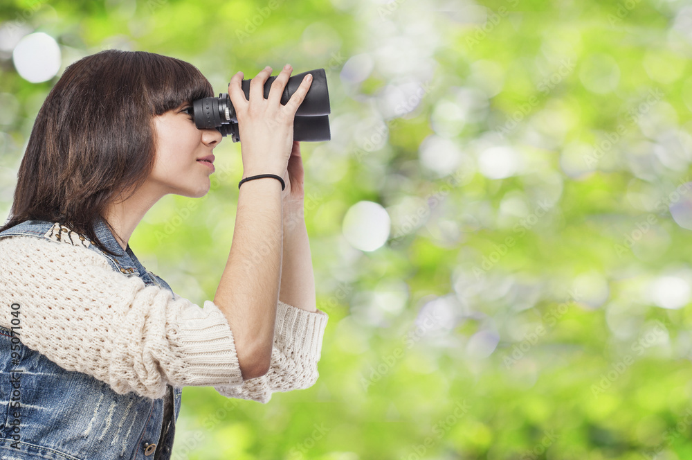 curious young woman looking through the binoculars
